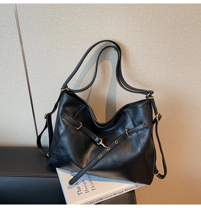 Detail of soft black leather tote bag with adjustable strap and brass metal hardware