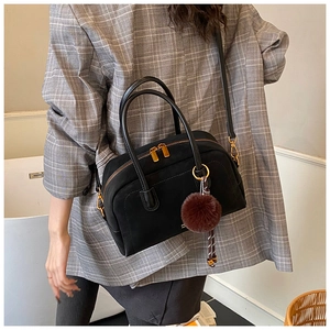Detail view of the black retro pillow bag with golden zipper and plush charm on a model