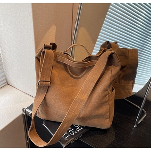 Detail of adjustable strap and side pocket on vintage brown canvas messenger bag