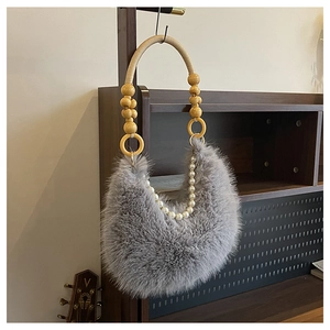 Détail du sac croissant en fausse fourrure grise avec chaîne perlée et anse tissée
