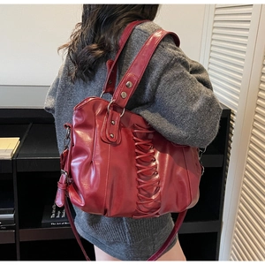 Detail shot of the dark red tote bag featuring punk-style criss-cross lace-up design and rivets