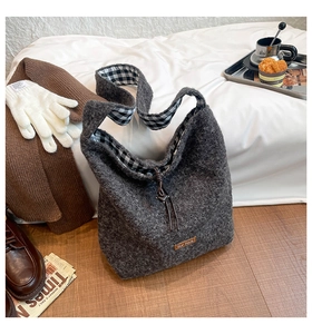 Detail view of a soft grey wool tote bag with plaid lining and drawstring closure