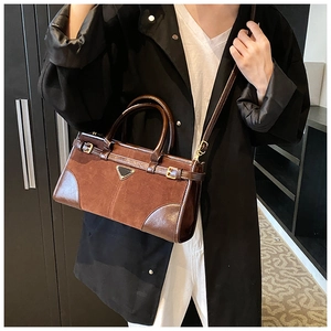 Detail of coffee-colored frosted crossbody bag with metal triangle plaque and shoulder strap