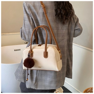 Detail of a vintage cream leather Boston bag with brown trim and plush pompom charm