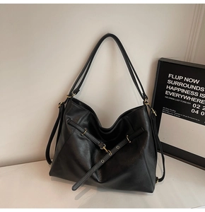 Detailed close-up of textured black leather tote with decorative straps and gold hardware