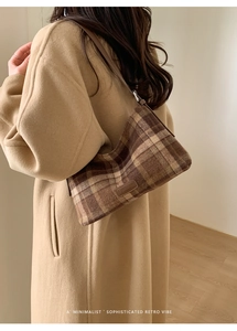 Close-up of retro plaid shoulder bag with vintage texture and stitched leather brand detail