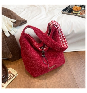 Detail of red plush tote bag with inner checkered lining and metal logo plate