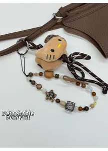 Vue détaillée d'un charm en peluche à chapeau léopard et d'une sangle perlée pour sacs
