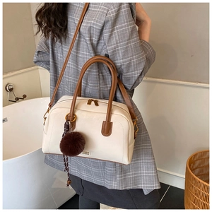 Chic cream pillow bag with dark brown handles and plush charm detail shown on model