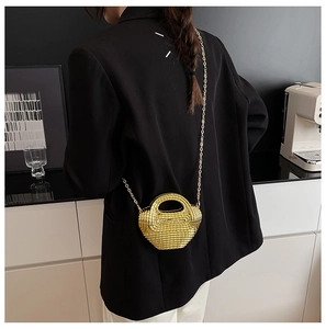 Dettaglio della mini borsa dorata con trama intrecciata portata da una modella