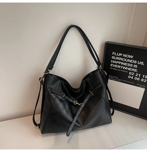 Detail of black faux leather tote bag showing fine grain texture and metal buckle