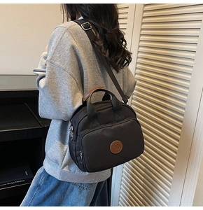 Detail of black nylon crossbody bag with leather logo and multi-zipper pockets