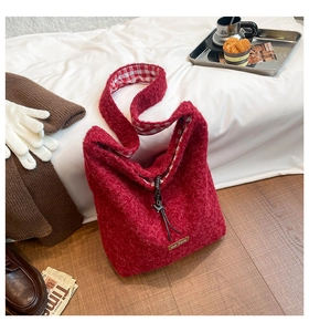 Detail of red plush tote bag with plaid lining and drawstring closure in a cozy setting