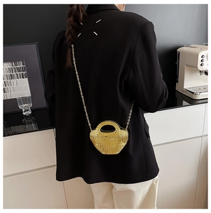 Dettaglio mini borsa a cestino intrecciata dorata con elegante tracolla a catena d'oro