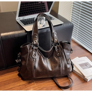 Détail d'un grand cabas vintage marron foncé posé sur une chaise dans un bureau
