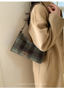 Close-up of vintage green plaid shoulder bag with leather logo patch and wool texture