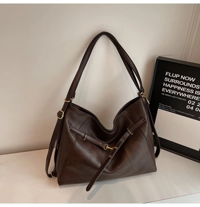 Detail of a large coffee brown leather tote bag with vintage metal buckles and retro style