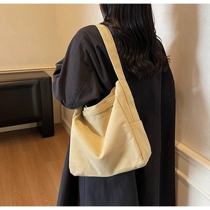 Minimalist beige canvas tote bag with side pocket shown in use on model shoulder