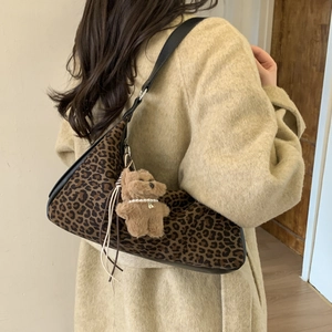 Leopard print dumpling bag with plush bear charm worn on a beige coat outfit