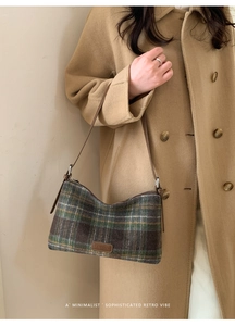 Détail d'un sac à carreaux vintage avec bandoulière en cuir sur manteau camel