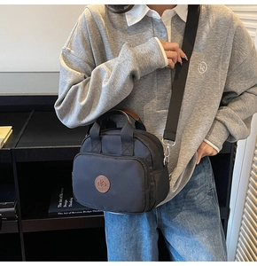 Detail of waterproof black nylon crossbody bag with dual handles and front zipper pocket