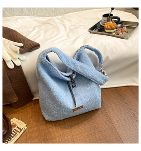 Detail of blue plush tote bag with brown leather label and checkered lining inside
