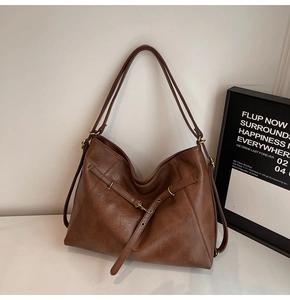 Detail view of brown leather tote bag with vintage bronze hardware and sleek texture