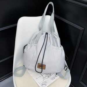 Detail view of light gray nylon drawstring bag showing leather logo and side toggles