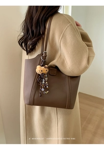 Détail du sac cabas en cuir marron avec charms élégants et bandoulière de qualité
