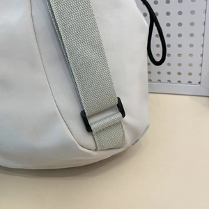Close-up of white waterproof nylon tote bag with grey strap and black plastic buckle