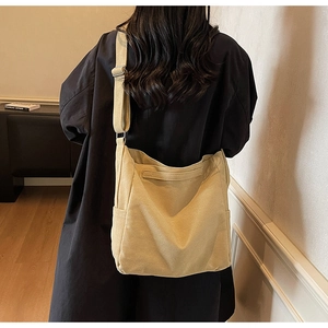 Close-up of yellow canvas messenger bag with adjustable strap worn on person