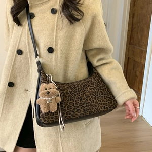 Detail view of leopard print dumpling bag with plush bear charm and pearl necklace