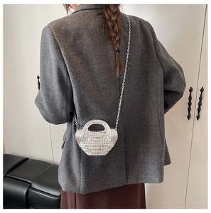 Mini borsa a mano argento con strass e tracolla a catena su un blazer grigio