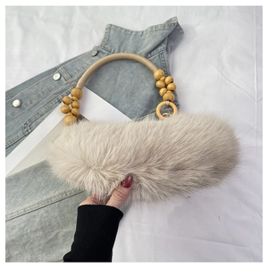 Détail d'un sac à main beige en fausse fourrure avec poignée en corde et perles en bois