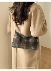 Close-up of winter plaid wool tote bag with a leather fashion tag on long camel coat