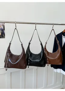 Detailed view of three minimalist hobo bags in brown, black, and caramel with tassels