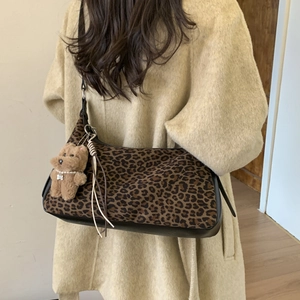 Detailed view of leopard print hobo bag featuring a plush bear and pearl charms