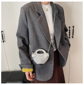 Dettaglio della mini borsa in paillettes argento con tracolla a catena e design curvo