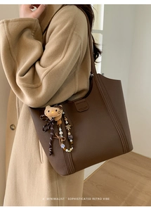 Détail du cabas en cuir grainé marron foncé avec breloque peluche et perles décoratives