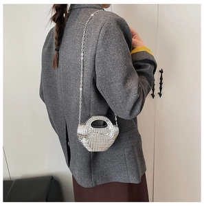 Dettaglio di una mini borsa argento intrecciata con manico tondo e tracolla a catena