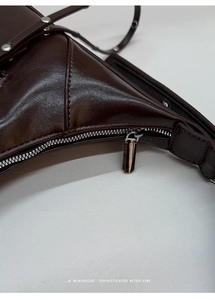 Close-up of a dark brown leather bag with silver metal zipper and precise stitching