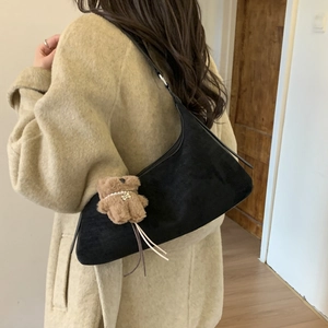 Detail view of black dumpling bag with cute plush bear pendant and slim shoulder strap