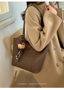 Détail du cabas en similicuir marron foncé avec texture litchi et pendentif chaton en peluche