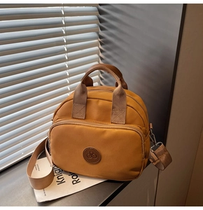 Detail of ginger yellow nylon crossbody bag with dual handles and detachable wide strap