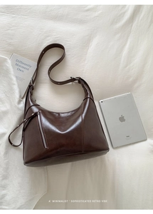 Detail of dark brown retro crossbody bag with front zipper pocket on a white sheet
