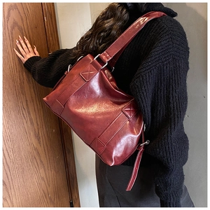 Detailed view of deep red vintage shoulder bag with visible stitching on smooth leather