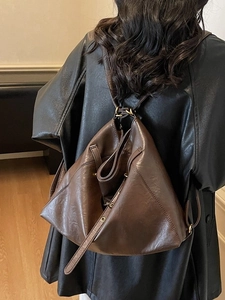 Deep brown retro leather backpack with soft pleated texture shown on model in black coat