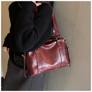 Close-up of a large burgundy tote bag in glossy leather with reinforced stitching detail