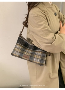 Side view of a vintage plaid underarm bag worn with a beige trench coat in a minimal setting