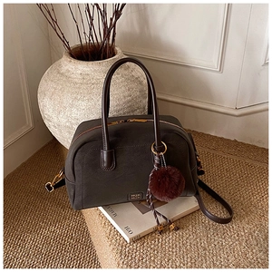 Close-up of a vintage dark brown leather boston bag with gold hardware and fur pompom